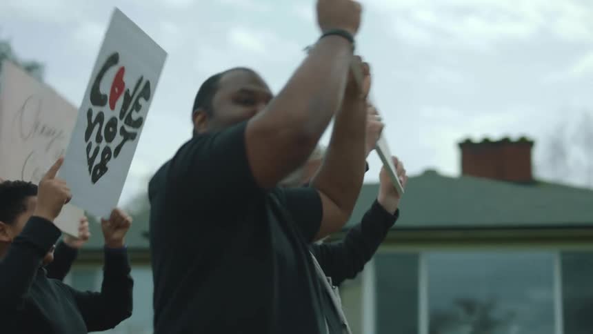 A group of people march together in protest in a neighborhood