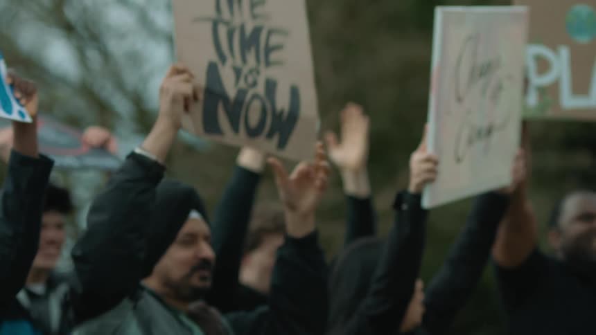 A group of people hold signs as they protest outdoors during the day