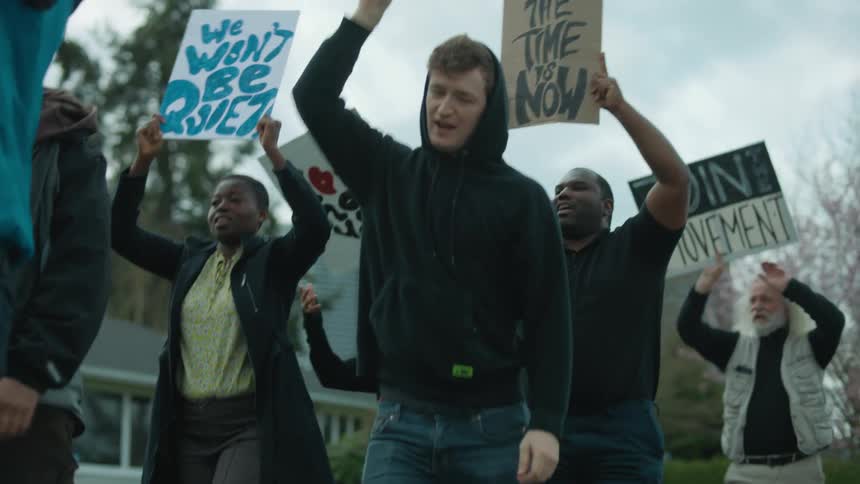 People hold up signs as they march in protest about a movement
