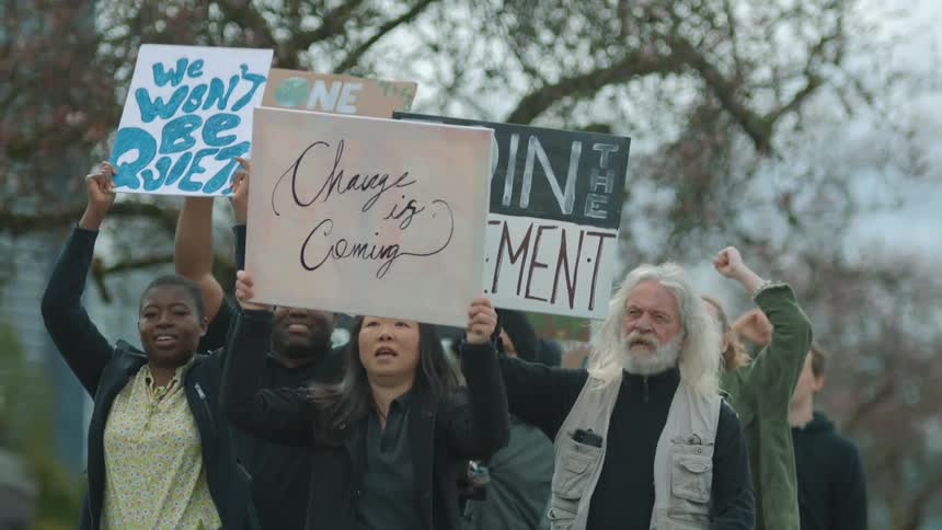 A group of protests hold signs as they march together through a city