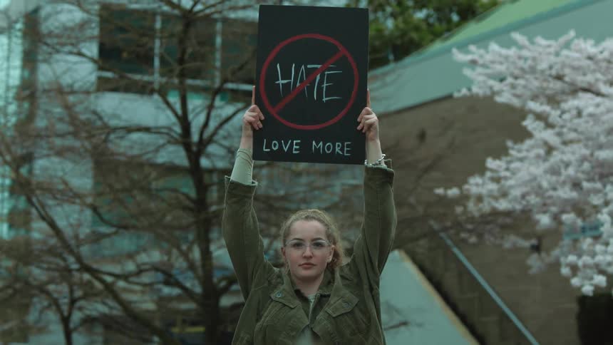 A young caucasian woman lifts up a sign