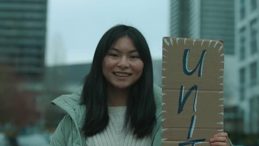 A woman is outdoors protesting in a downtown city