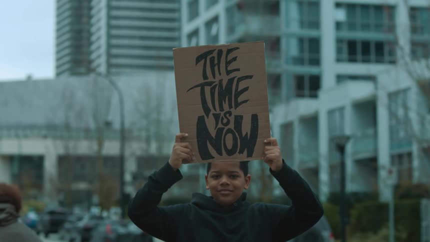 A child is outside protesting with a sign that he is holding