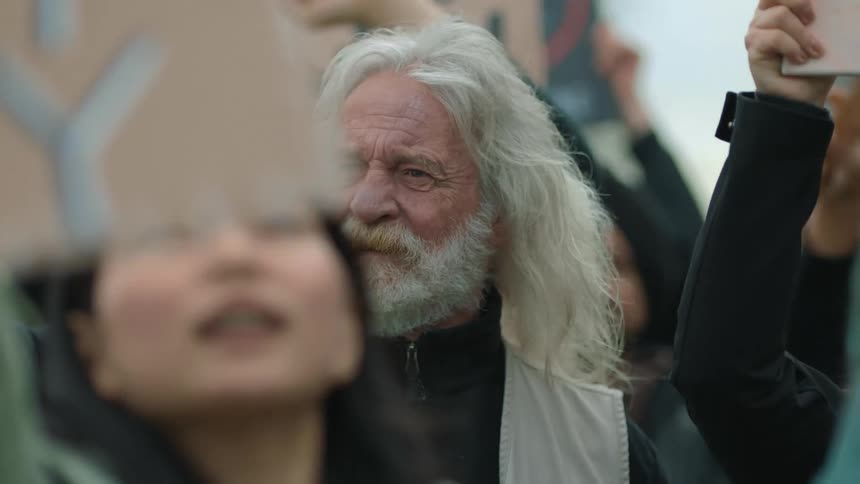 Men and women hold up cardboard signs as they stand closely together and protest