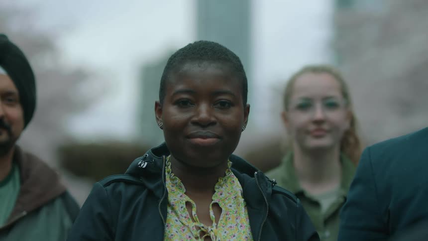 A group of people smile as they pose in a park
