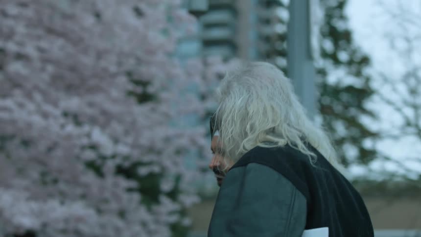Two men talk as they walk near some blooming trees