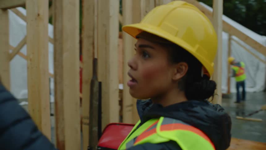 A male construction worker is showing the construction site to a female worker and she is nodding her head