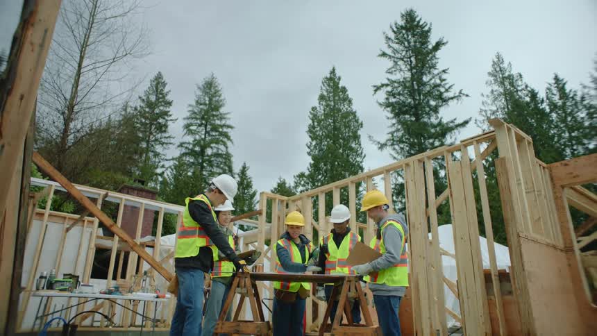 Construction workers chat around a table inside a structure