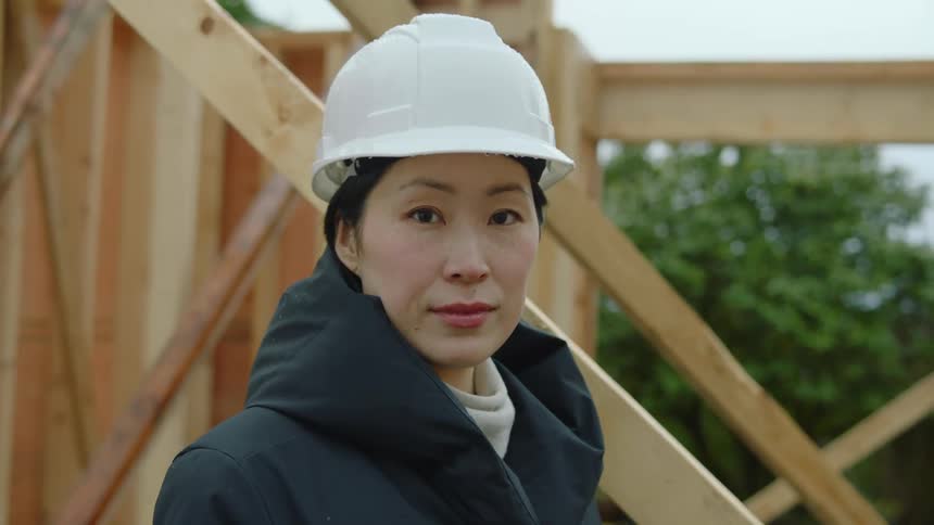 Female asian construction worker wearing a white safety helmet and standing in a construction site