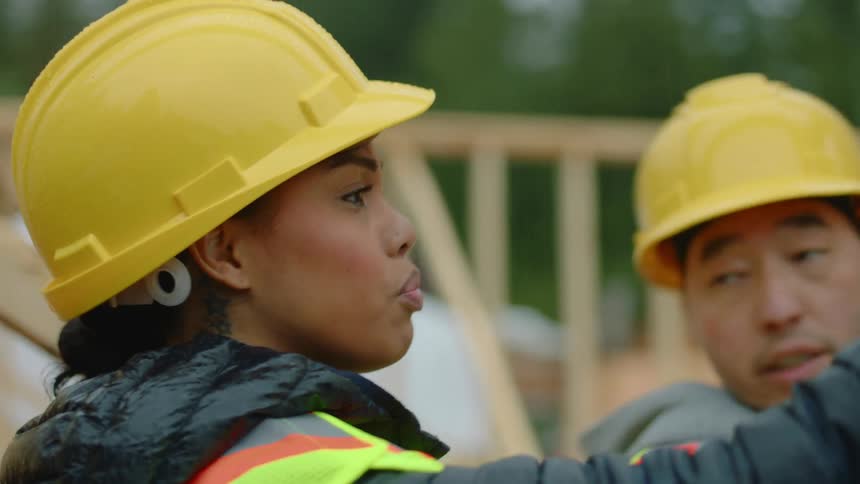 A female construction worker is giving instructions to her coworker