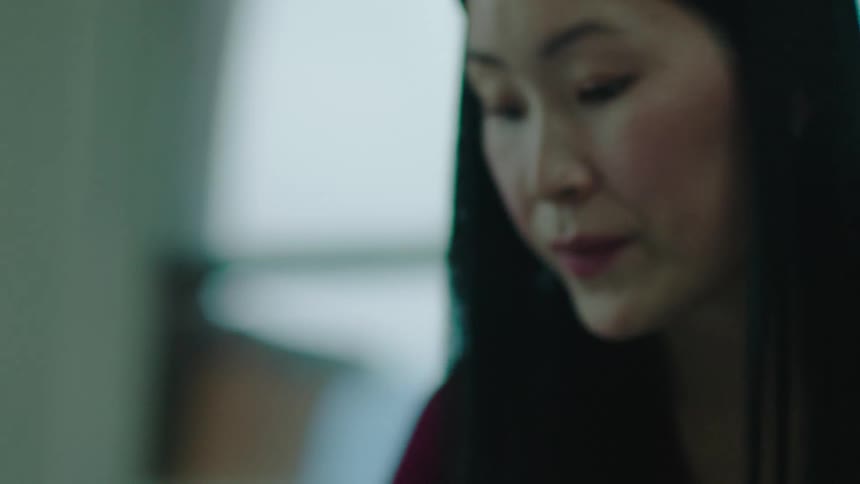 A woman looks at a paper on a desk and talks to an employee sitting there