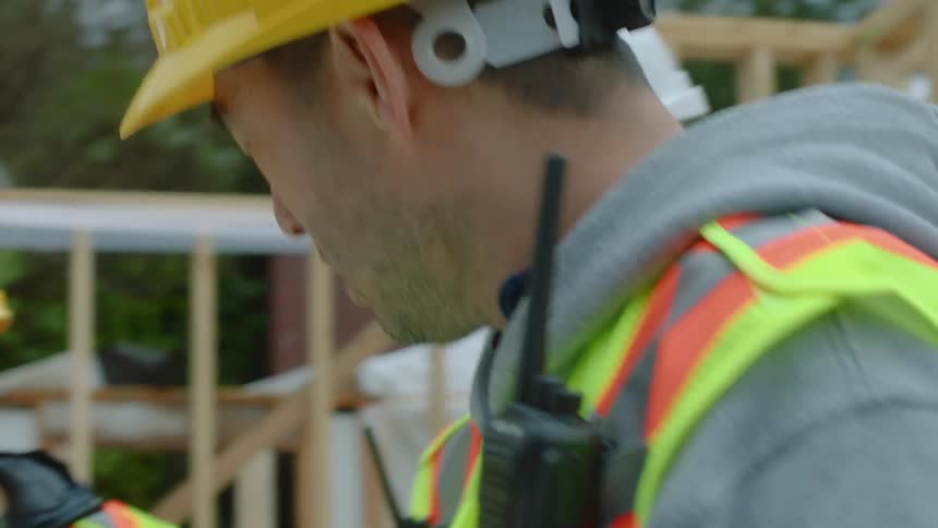 A group of construction workers are on site holding clipboards and talking