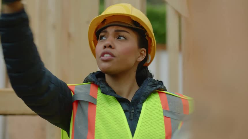A female construction worker is giving instructions to her coworker