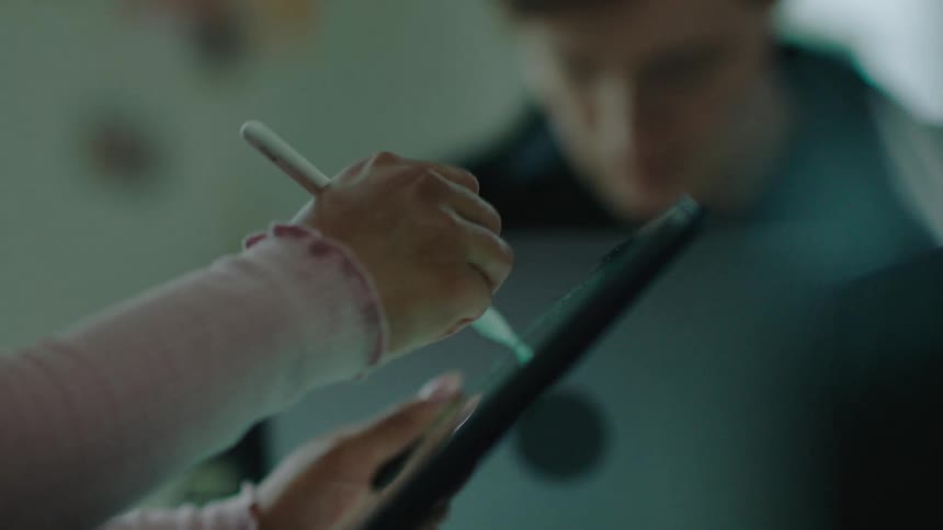 A woman takes notes on a tablet while talking during a meeting at work