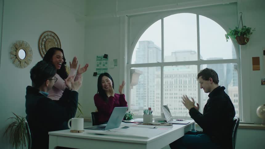 A woman makes an exciting announcement to her team and they all clap