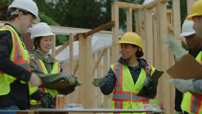 A female construction worker shakes the hands of her collegues at a site