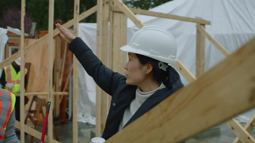 A male and female construction worker talk at a job site together