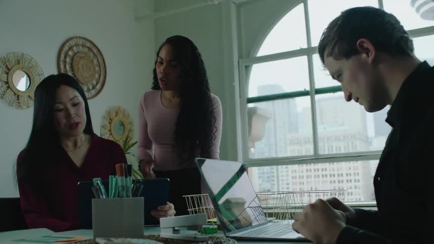 Two women collaborate in group office around a table