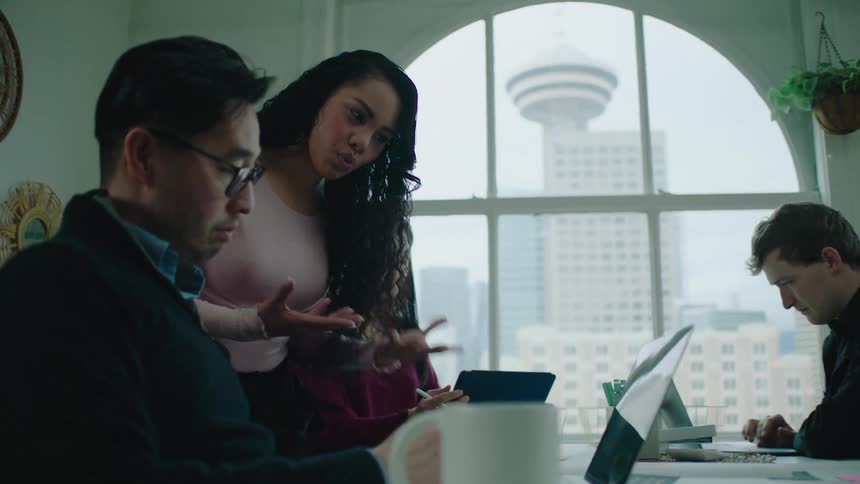 A woman collaborates with a male coworker in an office setting