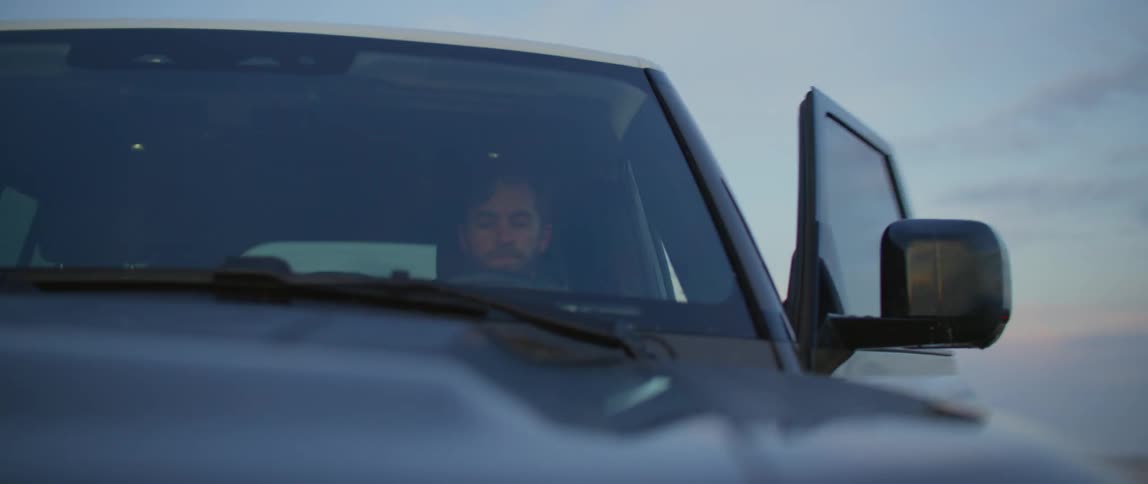 A man is getting out of his car outside and shutting the door