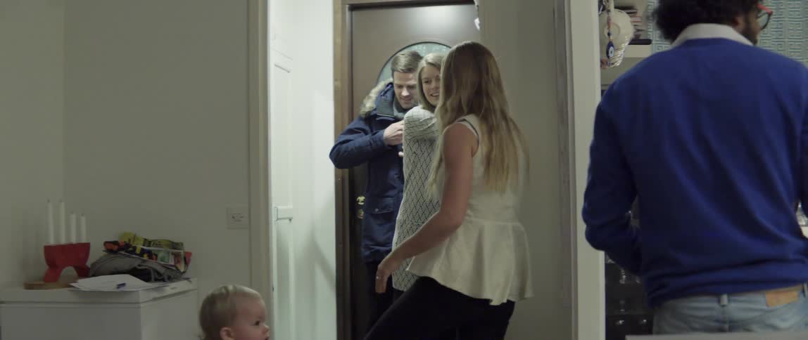 A couple walks into a house and is greeted by a child
