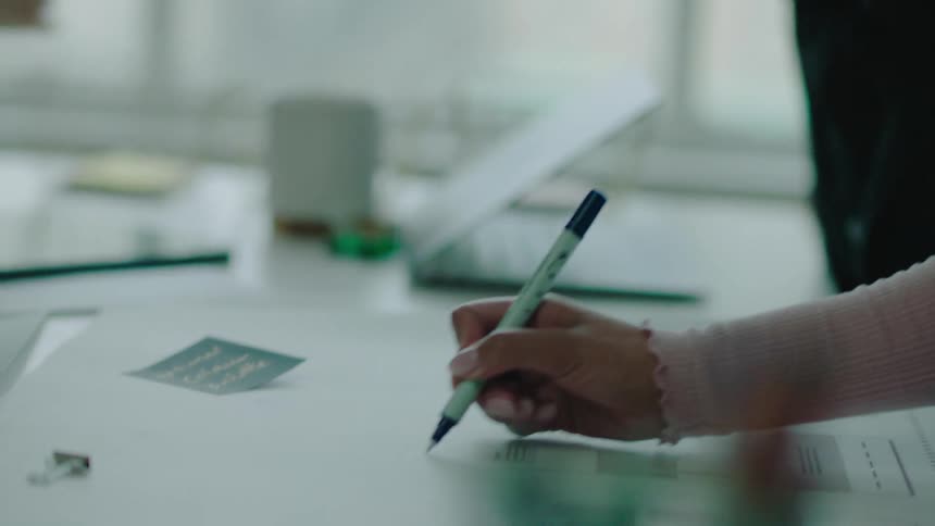 A woman takes notes on blueprints during a meeting