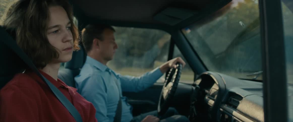 A pensive teenager looks sad as he rides in a vehicle with his dad
