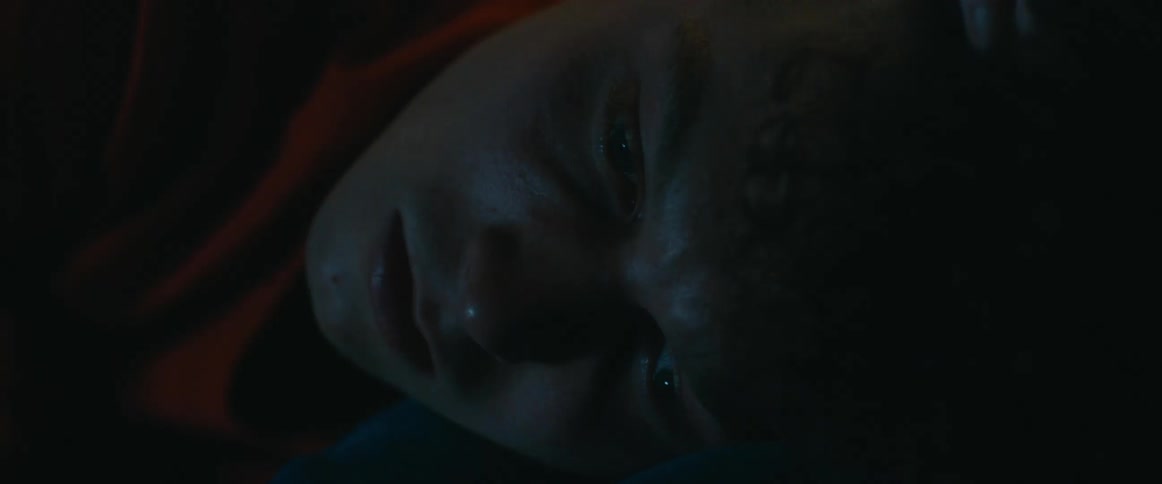A teenager girl strokes a boy's head as he lies on her lap