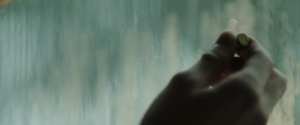 Hand holds up bullet against rainy window