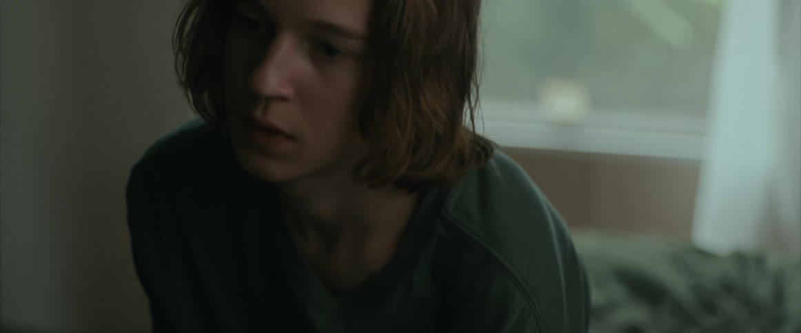A teenager sitting in his bedroom near a window