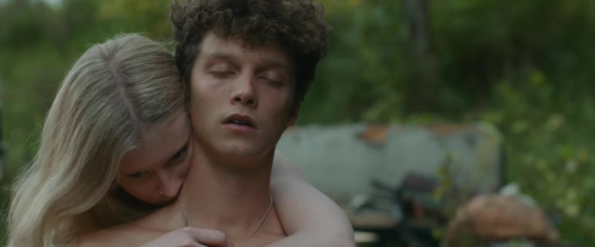 A teenage boy stands outside with his eyes close and breathes in deeply and then a teenage girl comes up behind him and puts her arms around him and hugs him