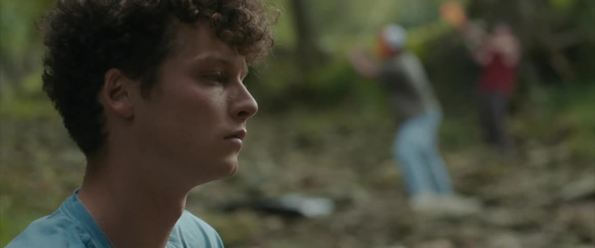 A boy sits by as something is being destroyed on the ground