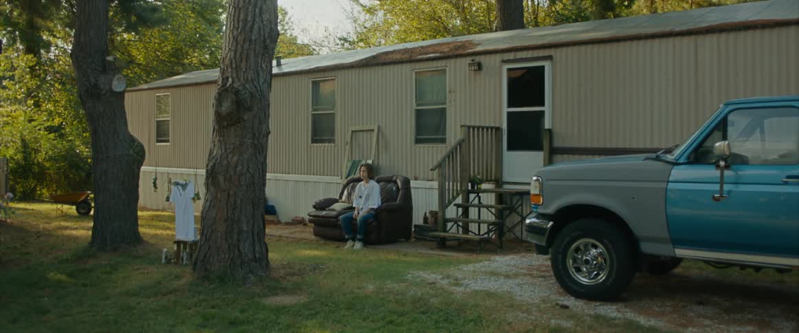 A person sits on a couch outside of a trailer home