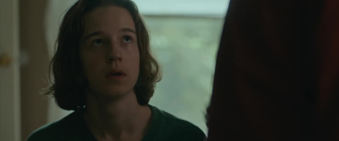 A teenage boy looking up at a man fearfully does not seem comforted when the man touches him