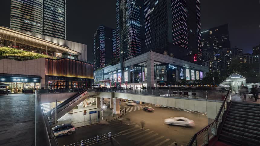 Pedestrians use a walkway over the intersection to move around as traffic speeds underneath in a city