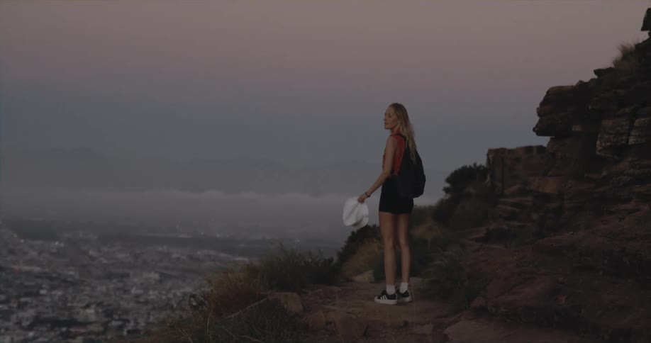 A young woman is hiking outside surrounded by some mountains