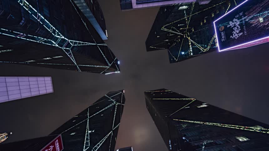 Looking up at lit skyscrapers against a cloudy night sky