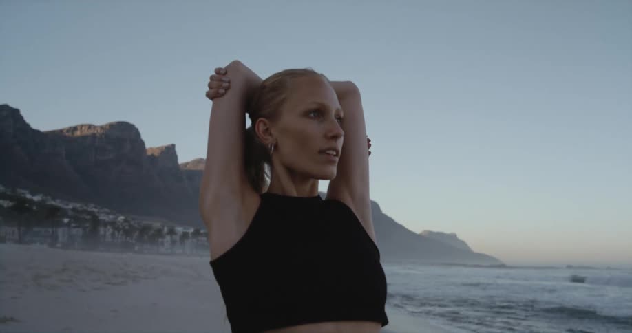 A young woman is stretching outside in front of the ocean