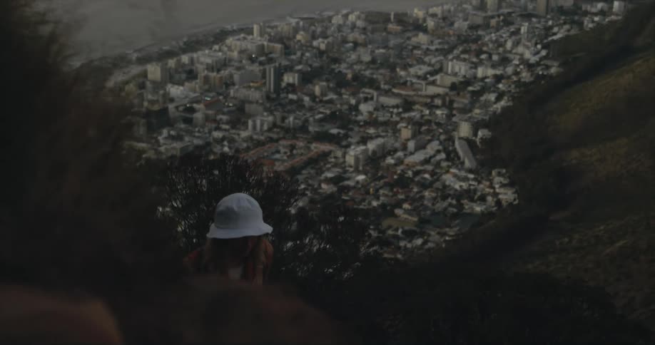 A woman is hiking up the mountain by the city