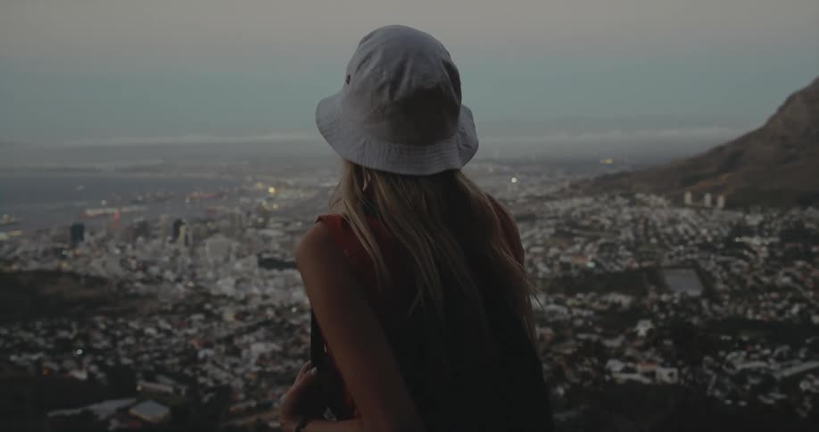 A woman is looking at the horizon at dusk