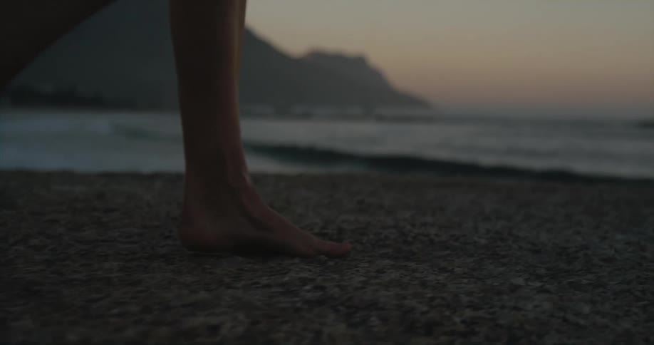 A person is walking at the beach at dusk
