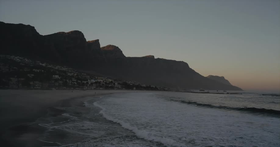 Foamy sea waves break against the beach at dusk
