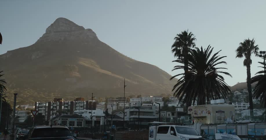 A mountain looms over the buildings of a city during the day