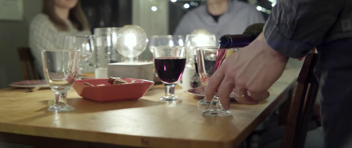 Person Pouring Red Wine Into Glasses on a Dinner Table With Warm Welcoming Vibes.