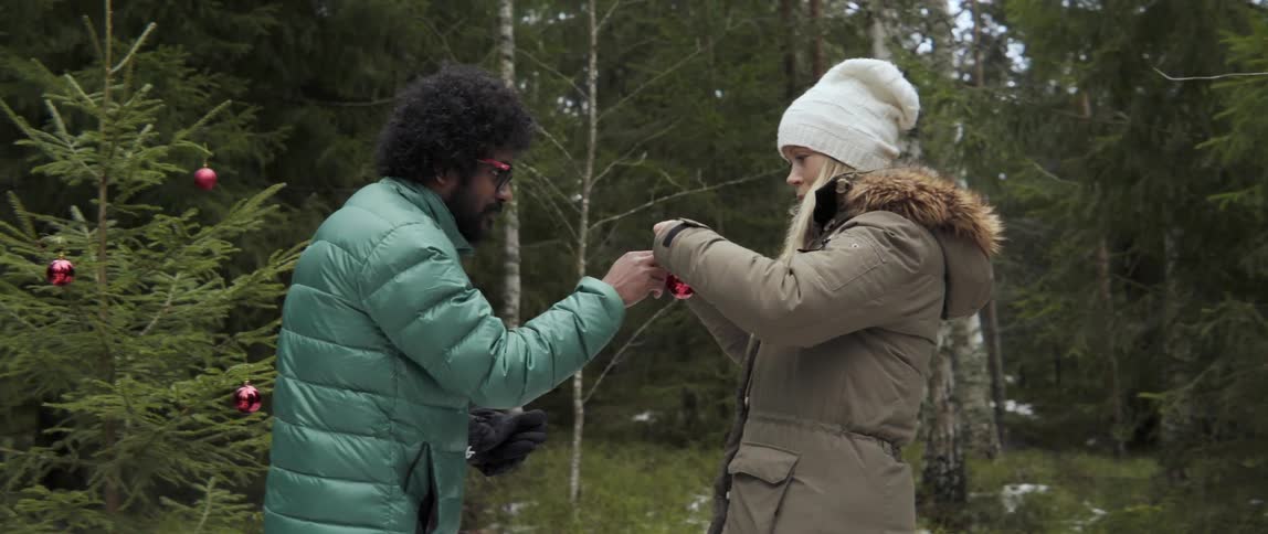 A man and woman adjusting something on an ornament as they stand outdoors
