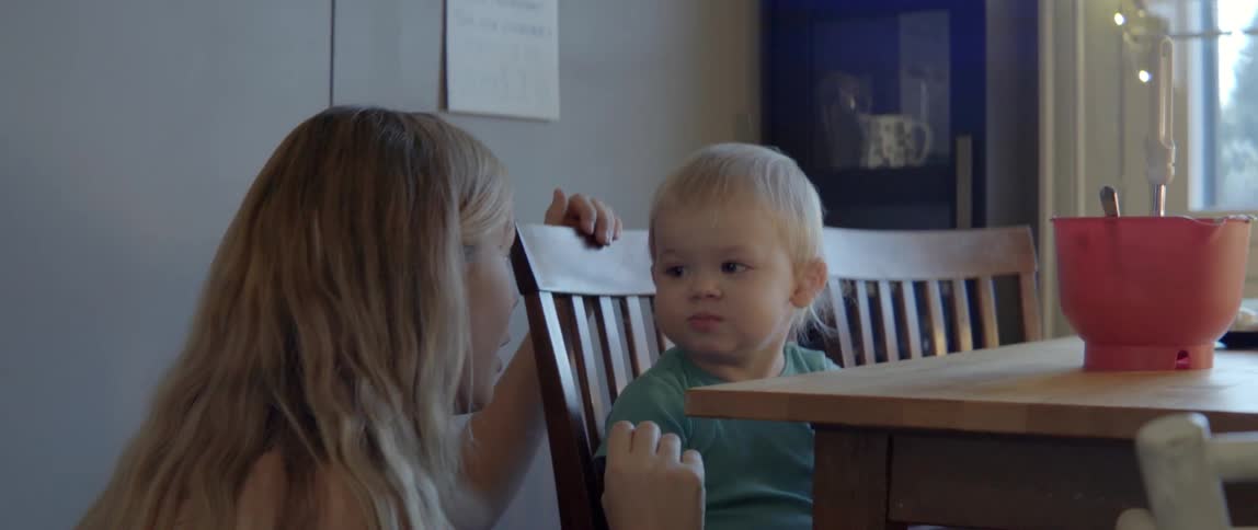 A woman talks and interacts with her young son while they share a snack.