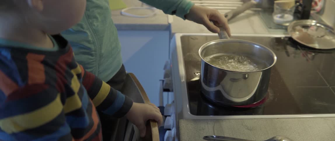 domestic scene of a toddler observing daily cooking routines in a bright kitchen.