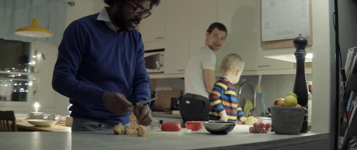 Joyful family interaction while preparing a healthy meal together in a sunny home kitchen.