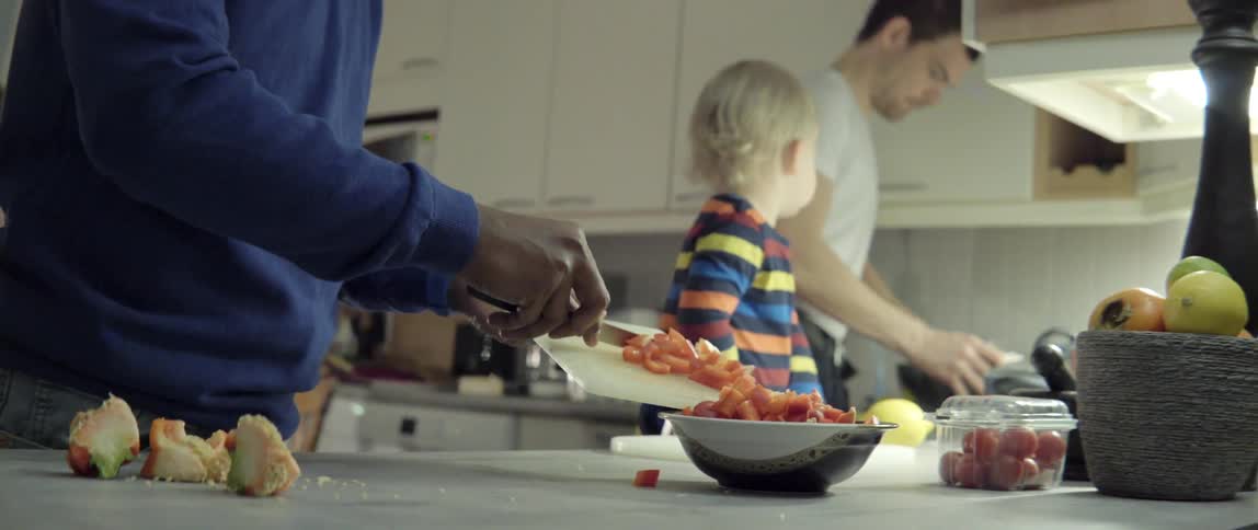 People Cooking and Preparing Food Together While a Child Watches With Warm Family Joy.