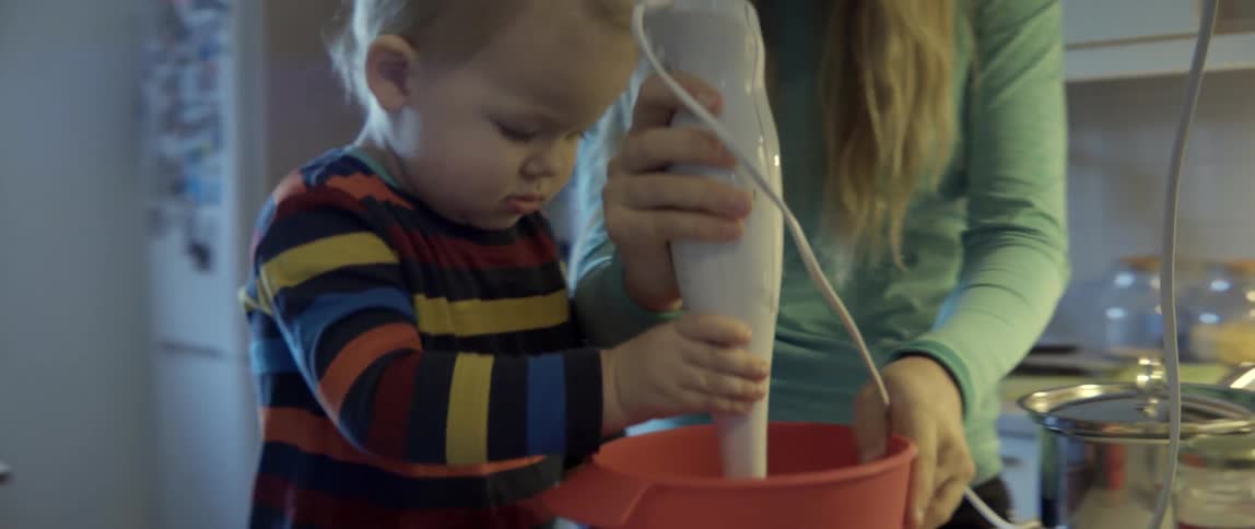 Heartwarming domestic scene of a child helping his mother bake in a modern kitchen.